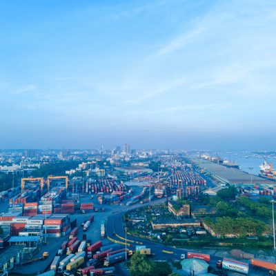 Vue aérienne d’un port logistique avec conteneurs, grues, camions et navires – Nexline Group