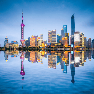 Vue nocturne de Shanghai reflétée sur l’eau, symbolisant la présence de Nexline en Asie